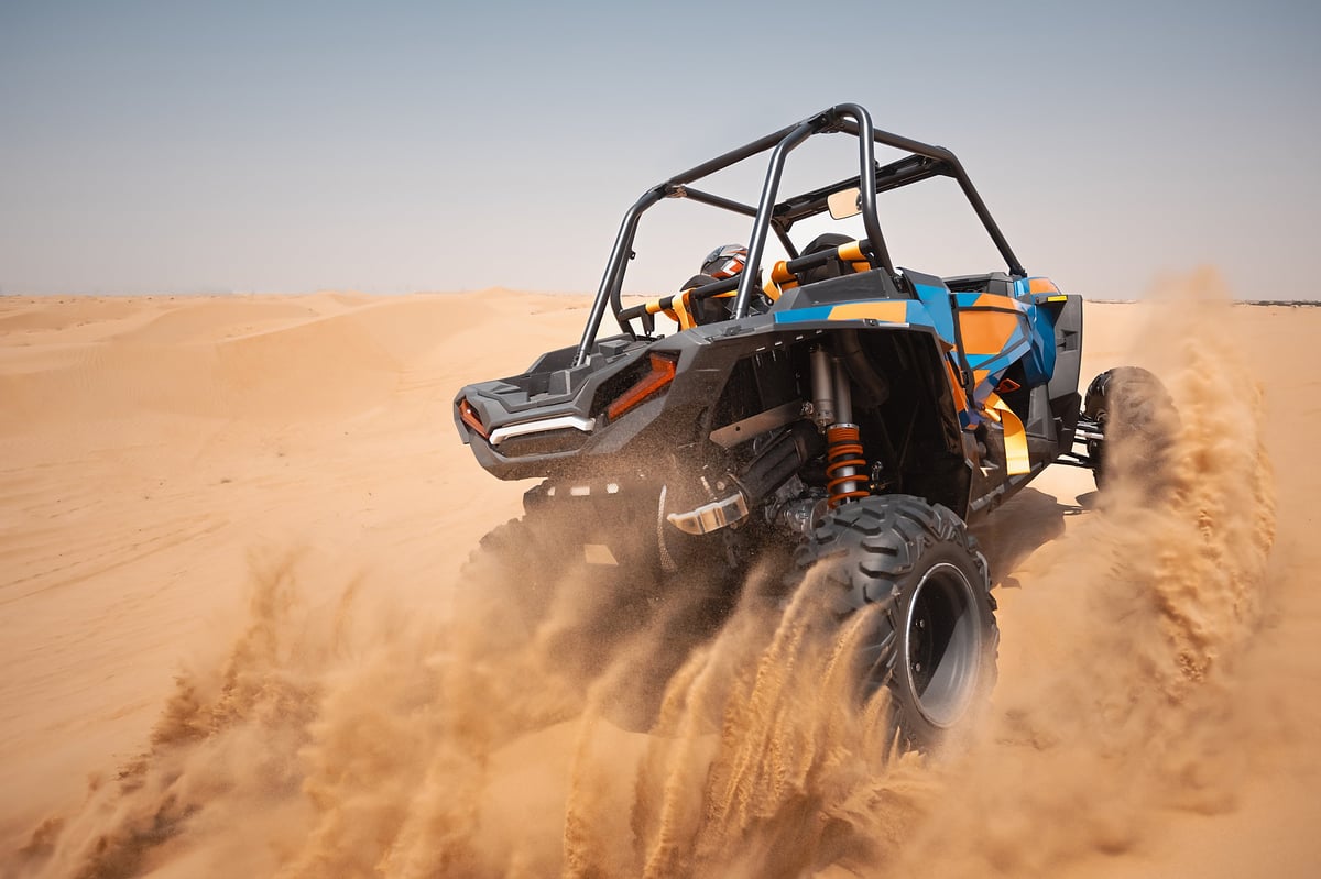 Off road Polaris buggy crossing soft open desert terrain on a Dubai dune buggy tour