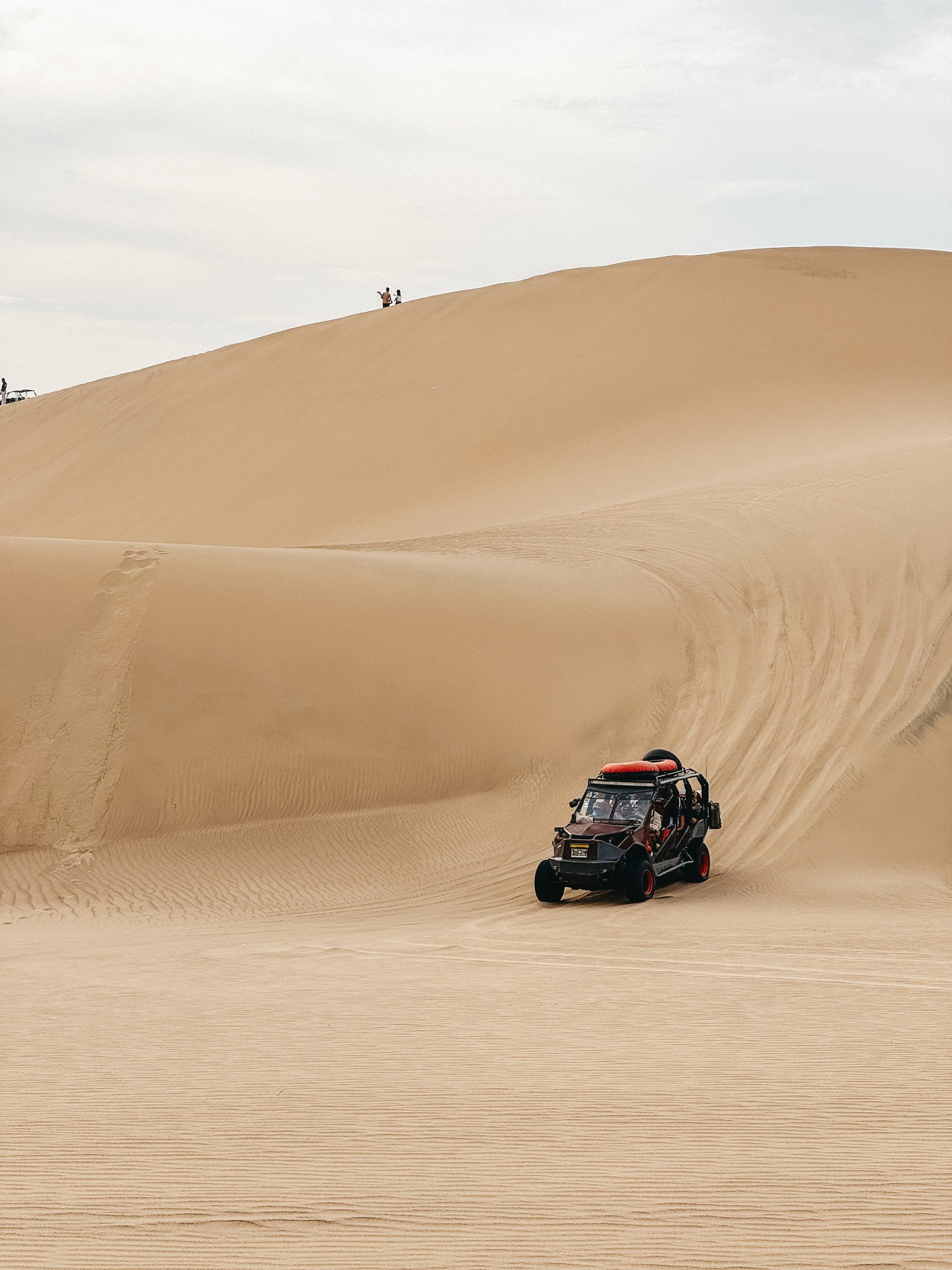 Dune buggy driving across red sand dunes near Sharjah at golden hour