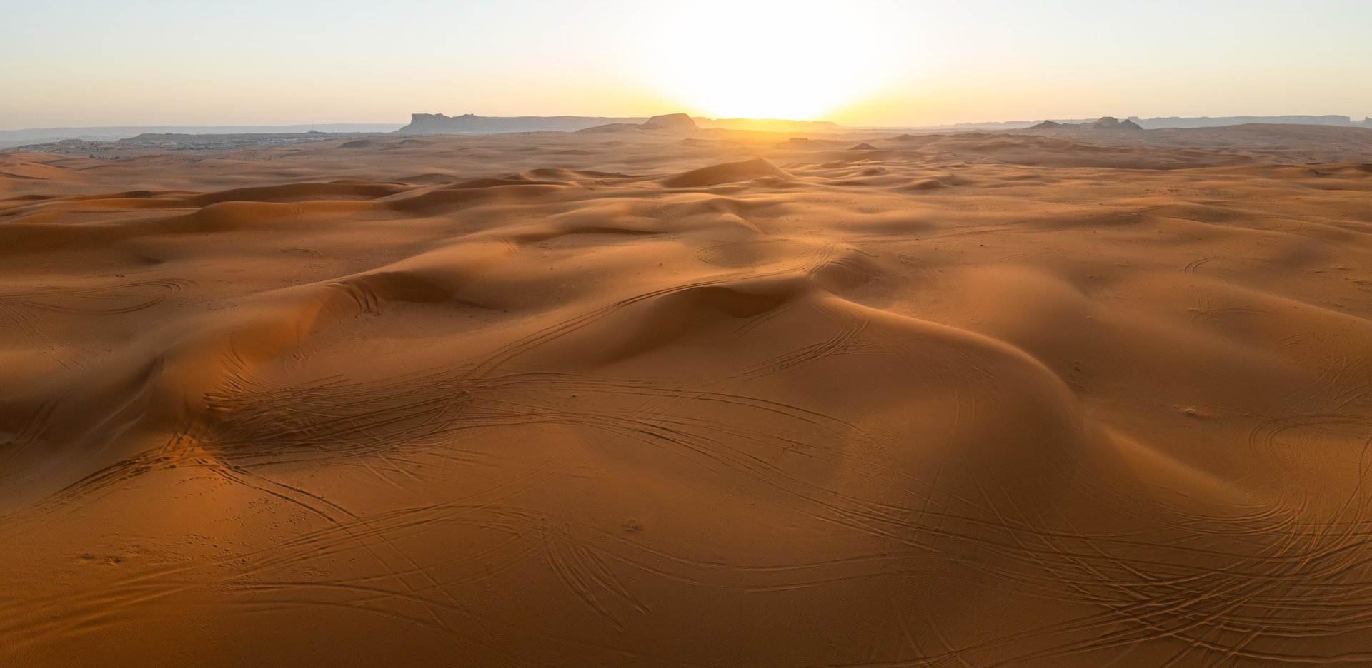 Sunrise Over the Saudi Desert Captured by Drone. Golden rays of the rising sun illuminate the rolling dunes