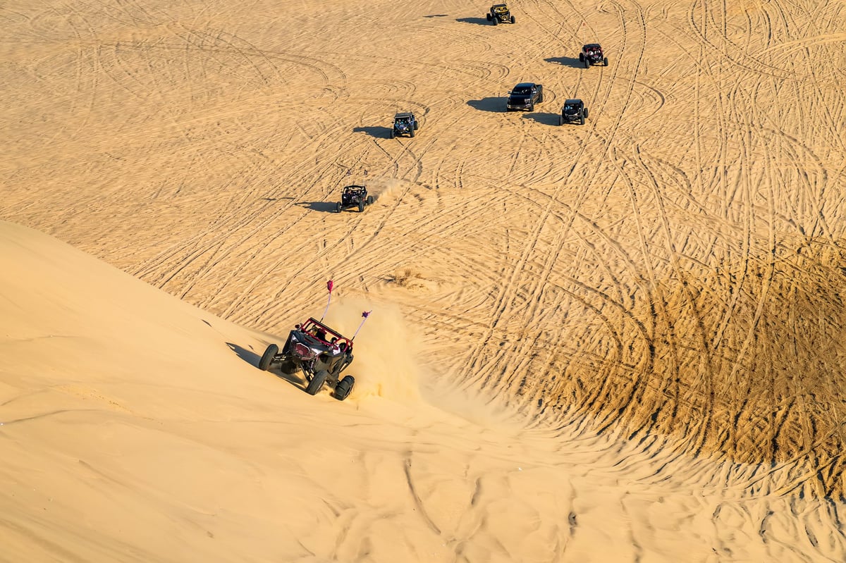 Polaris RZR XP Turbo buggy racing at speed over a sand dune in the Dubai desert