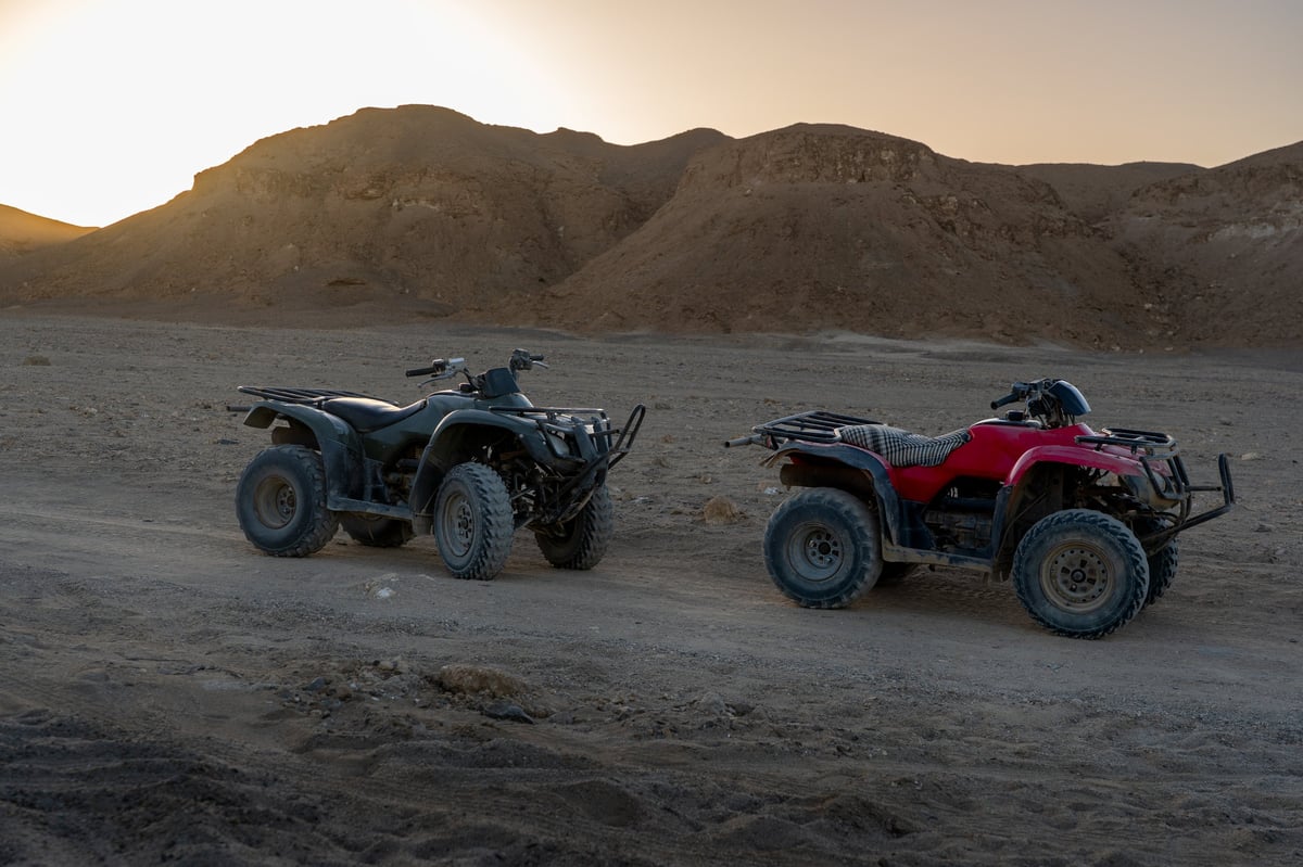 two quad bikes parked in a vast rocky desert landscape during golden hour