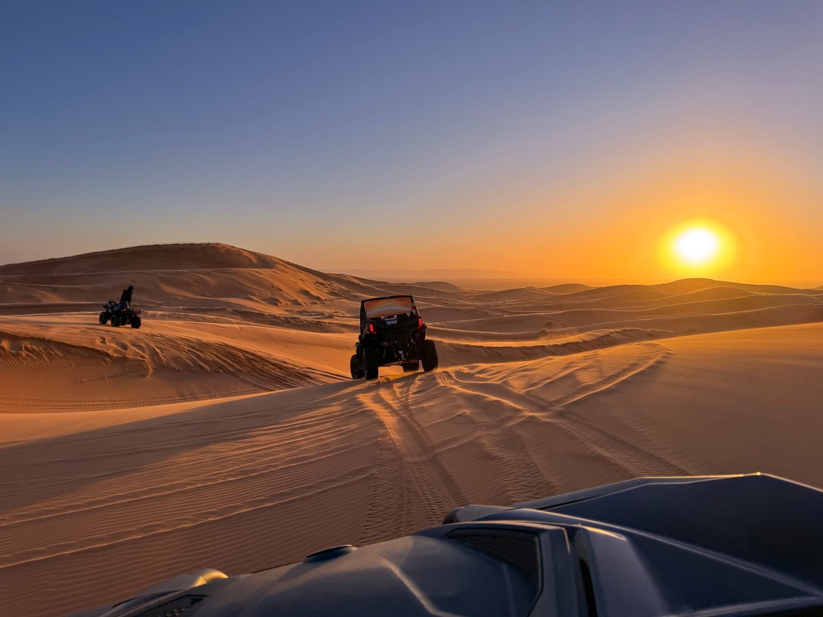 Polaris RZR buggy driving across golden desert sand dunes at sunset near Lahbab Dubai