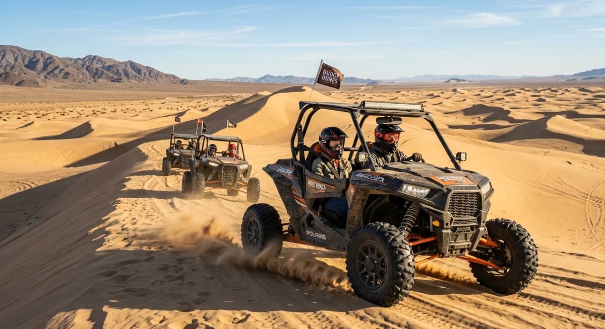 Two all-terrain buggies racing across sand dunes in a desert landscape with mountains in the background