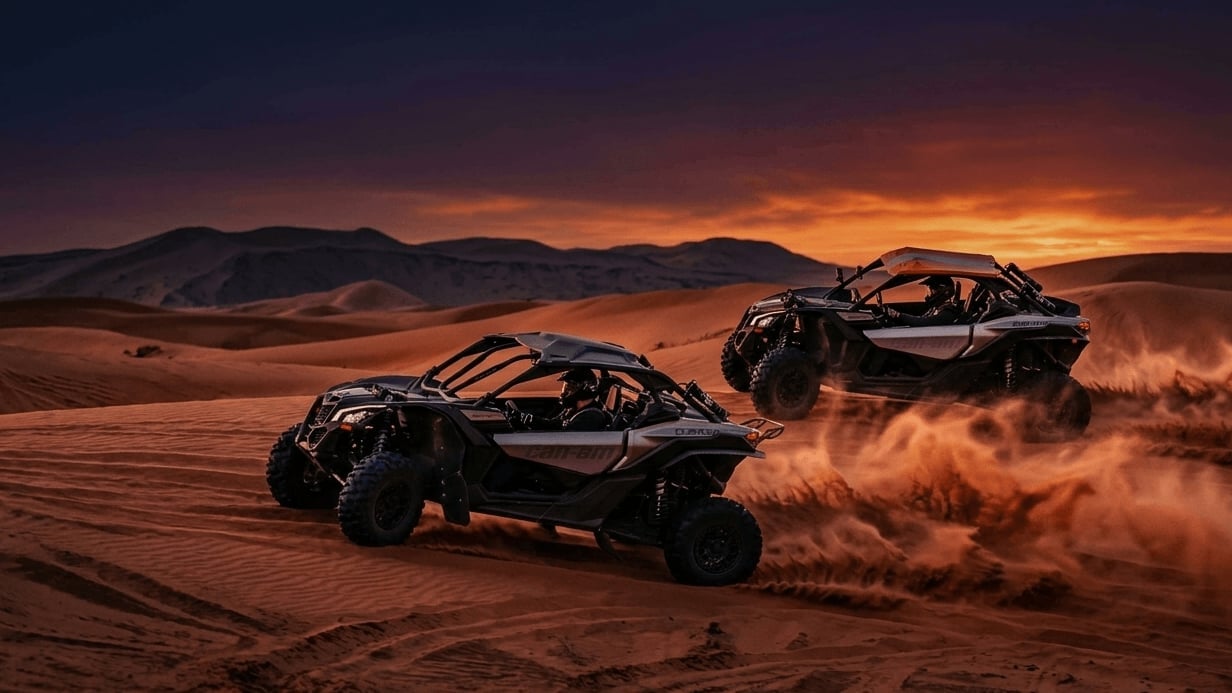Two buggy vehicles kicking up dust racing through desert landscape at sunset